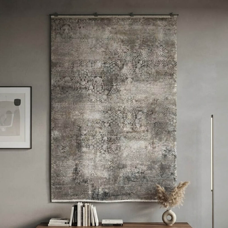 This rug features an understated abstract design in cream and grey tones, finished with a defined geometric border along the edges. The pile is intentionally low and soft, giving it a smooth, premium feel underfoot. It delivers a clean, high-quality look using simple, neutral colors.