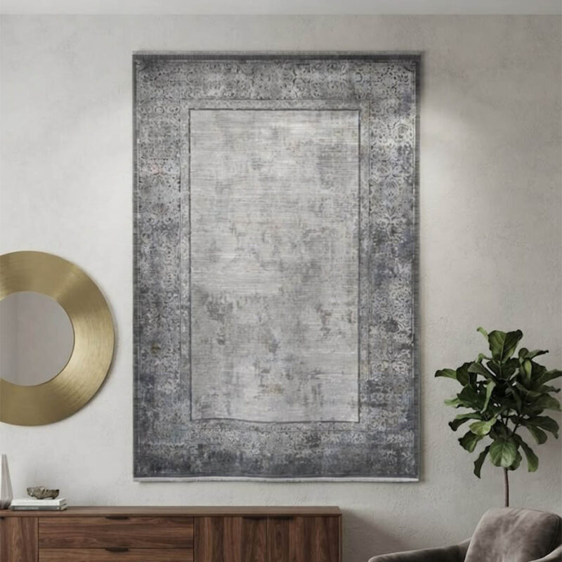 A high-quality area rug with a soft, uniform surface that feels smooth to the touch. The design showcases a distressed, abstract blend of grey and off-white in the center, bordered by a sharp, geometric frame. It offers a premium look and a comfortable feel without unnecessary embellishments.