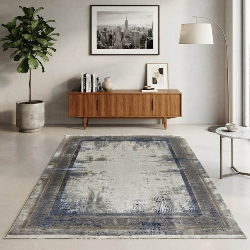Modern abstract area rug in grey and beige tones styled in a minimalist living room with a grey sofa and wooden credenza.